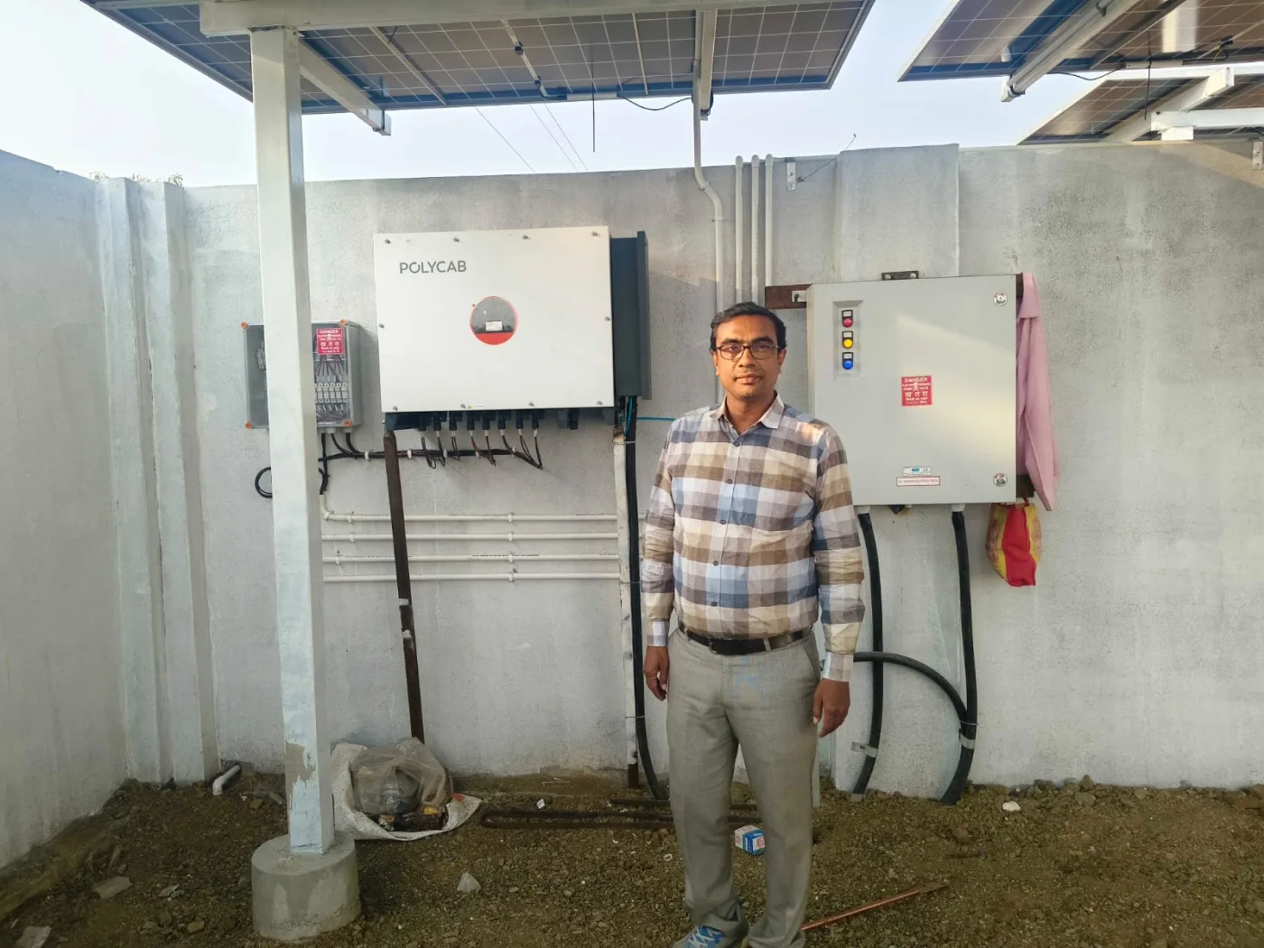 Polycab इन्व्हर्टर आणि सौर विद्युत नियंत्रण कपाटाजवळ उभा असलेला व्यक्ती