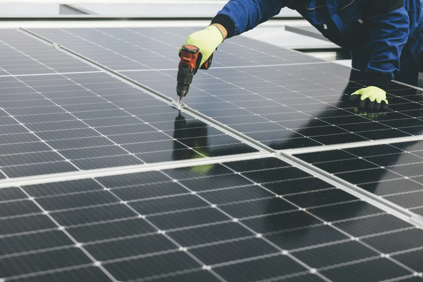 Illustrative close-up of a technician fastening a solar module